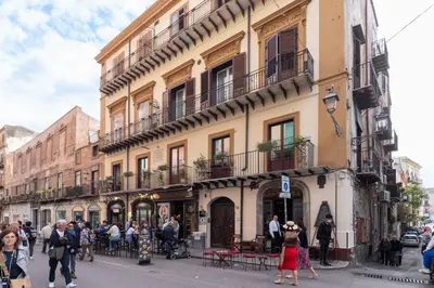 a group of people walking down a street in front of a building at Iverlid Home. in Palermo